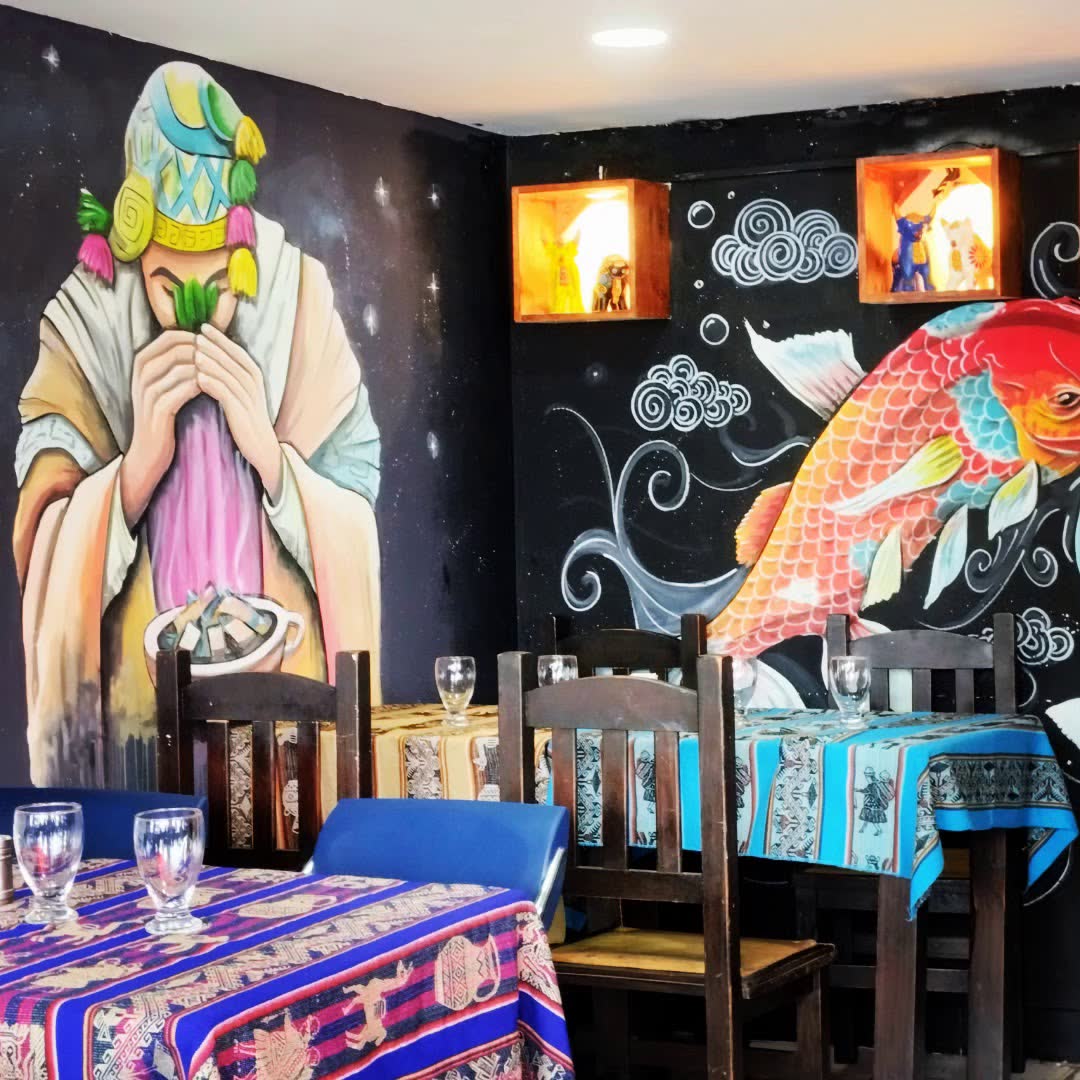 Salón con murales peruanos y mesas con manteles andinos