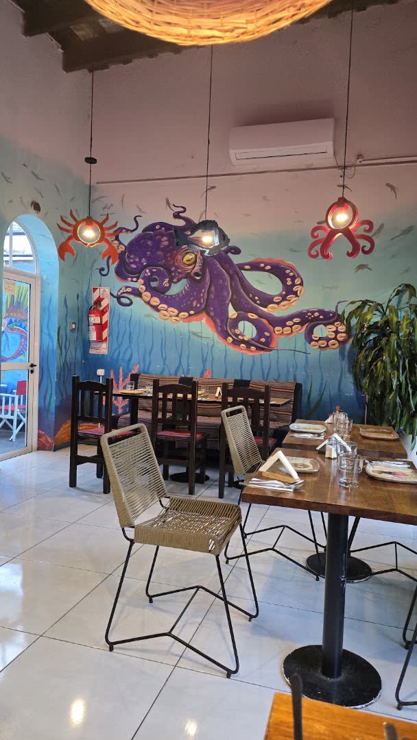 Salón de Palermo con mural de un pulpo y lámparas de mimbre